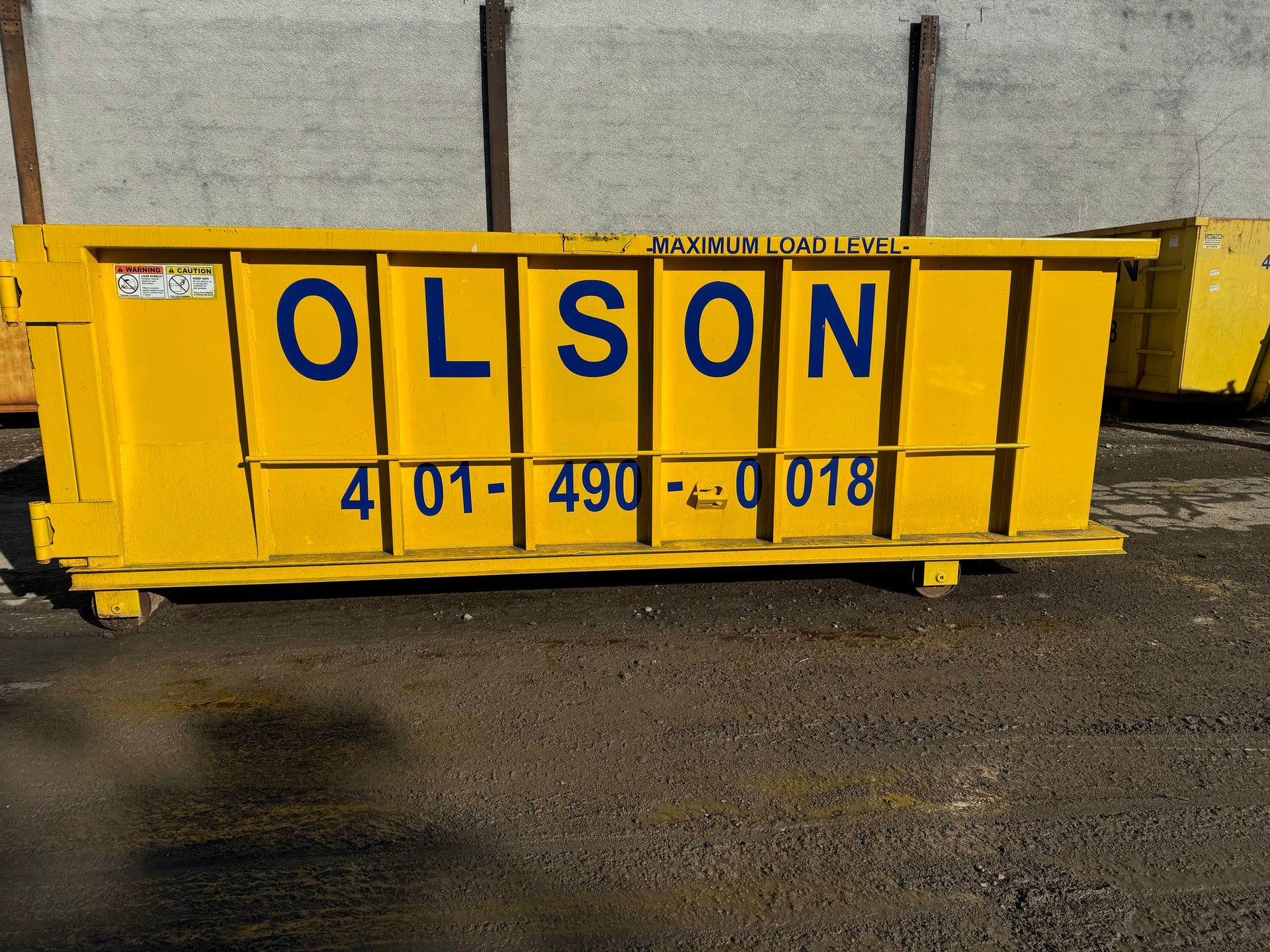 A 15-yard yellow dumpster with the name Olsonlson on it