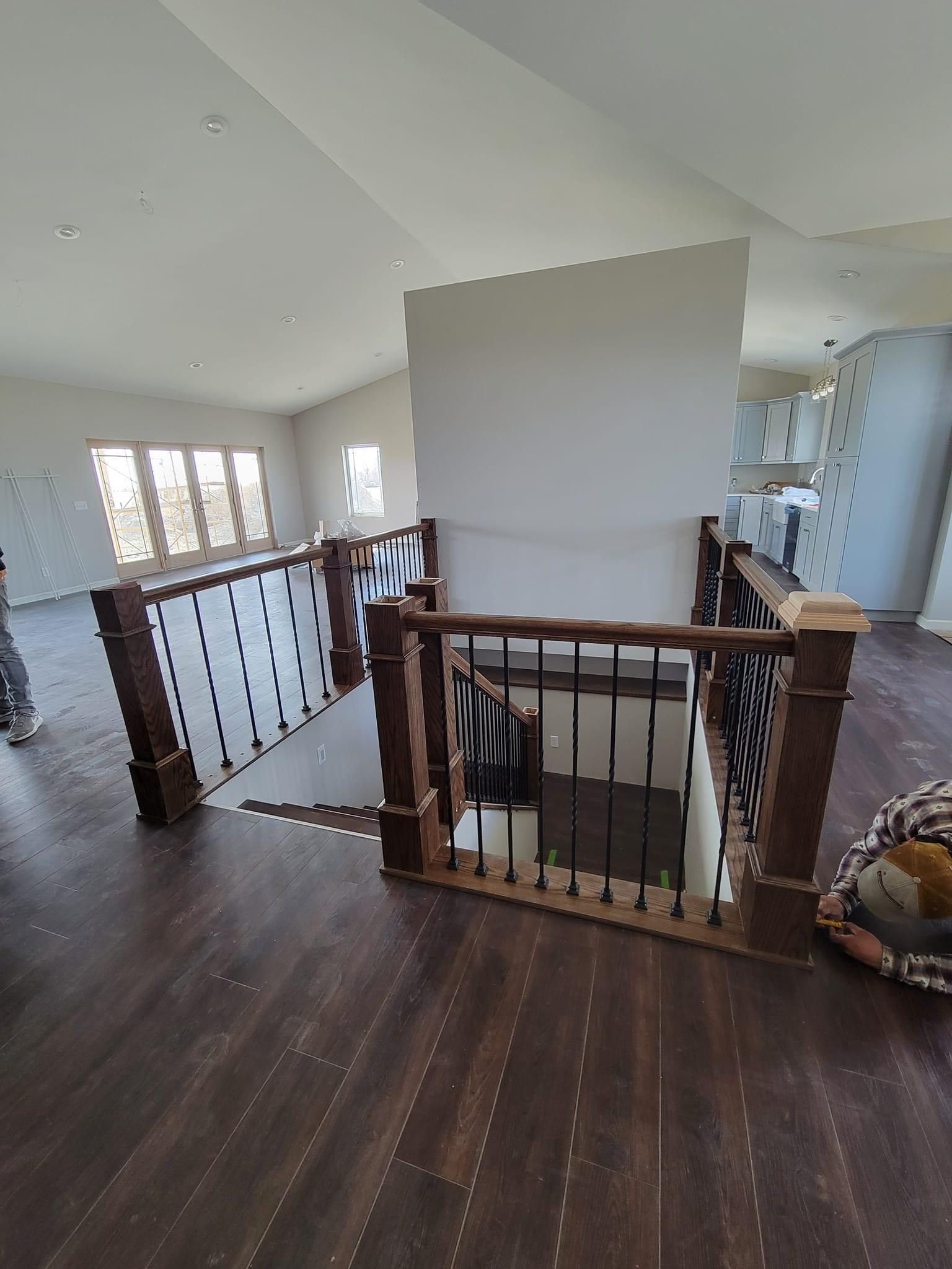 A man is kneeling on the floor next to a staircase in a house.