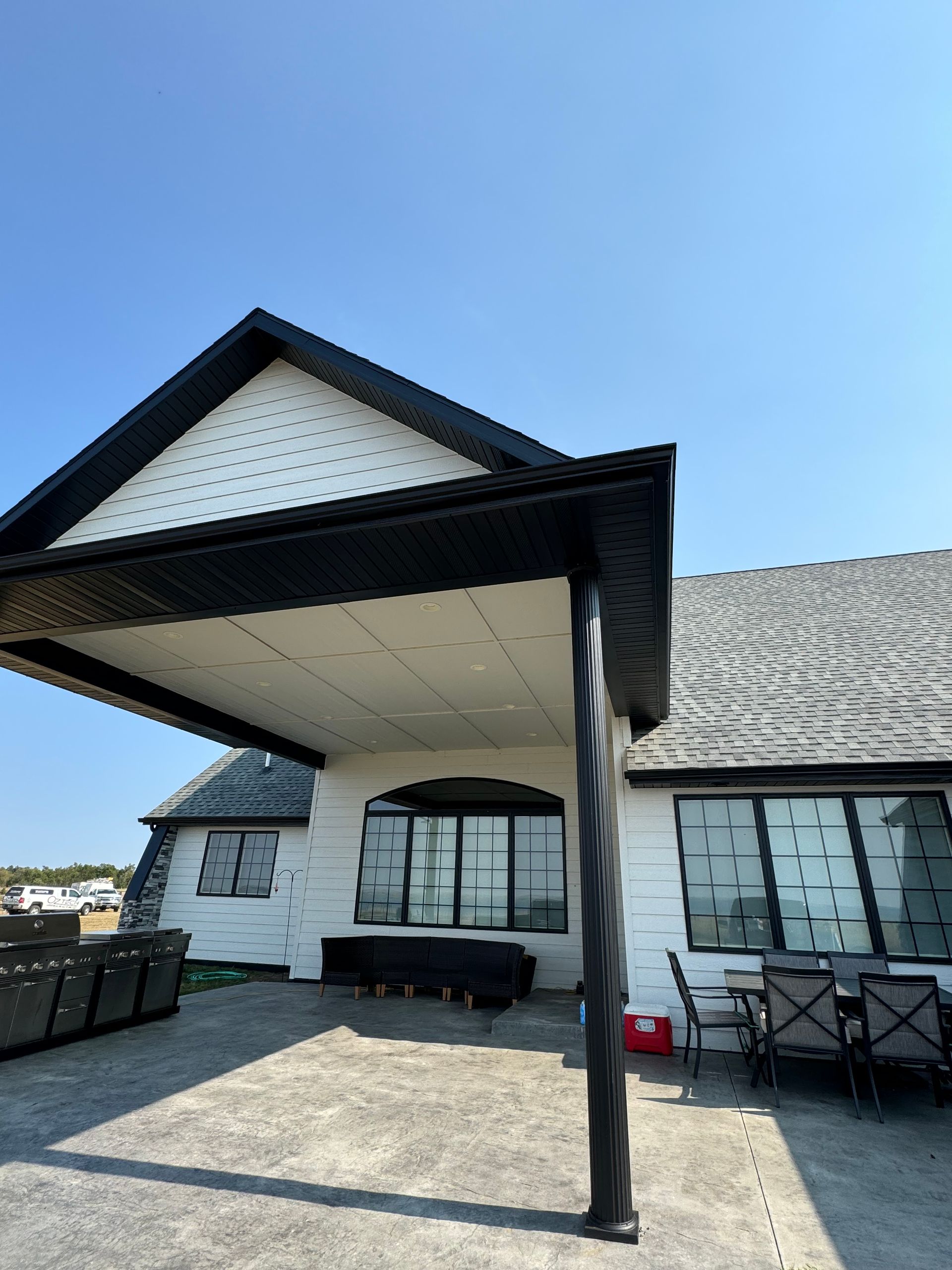 A white house with a black roof and a covered porch
