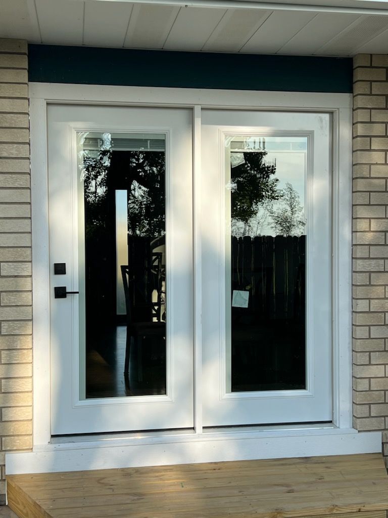 A white sliding glass door with a brick wall behind it