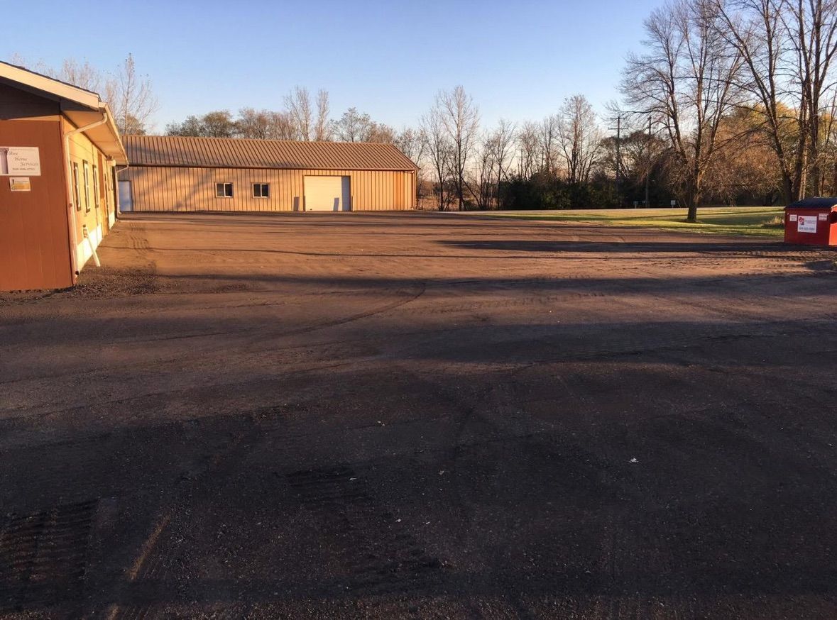 Empty asphalt parking lot with buildings in background on a sunny day.