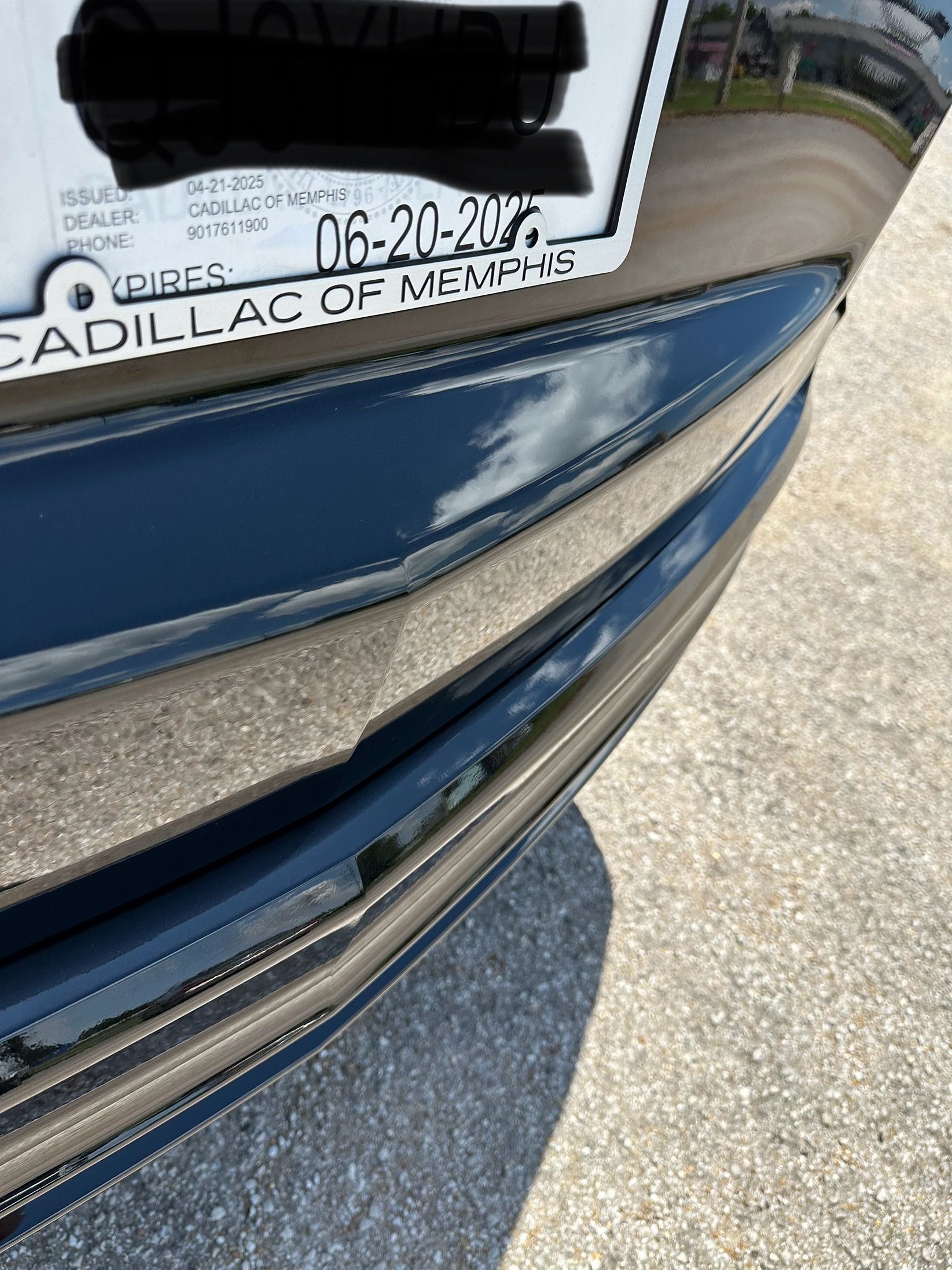 A close up of a blue car with a license plate that says cadillac of memphis.