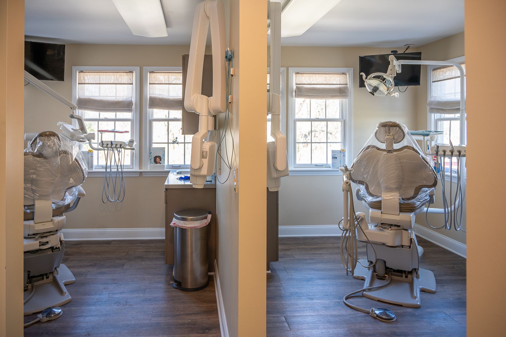 A dental office with two dental chairs and a trash can