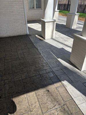 Stone patio with pillars, shaded, with light and dark grey brick pattern.