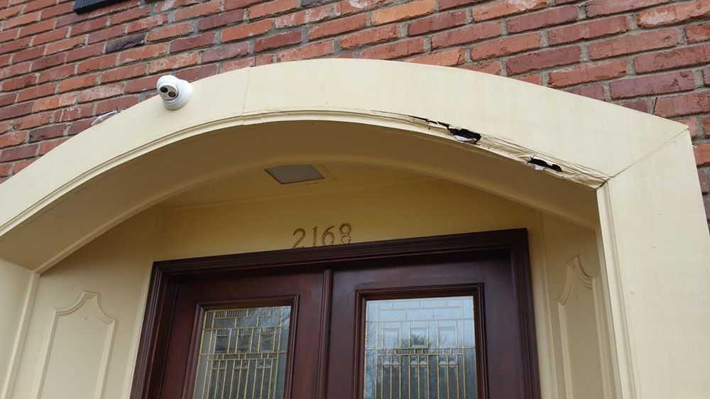 Camera above double doors with the number 2168 on a building's entryway.