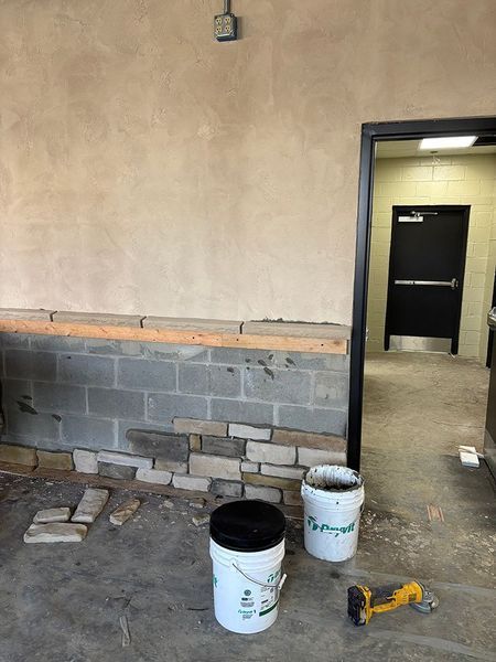 Construction site: Stone veneer installation on cinder block wall, next to a doorway.