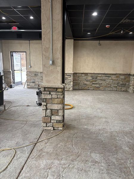 An empty room with stone accents, a support column, and an unfinished concrete floor.