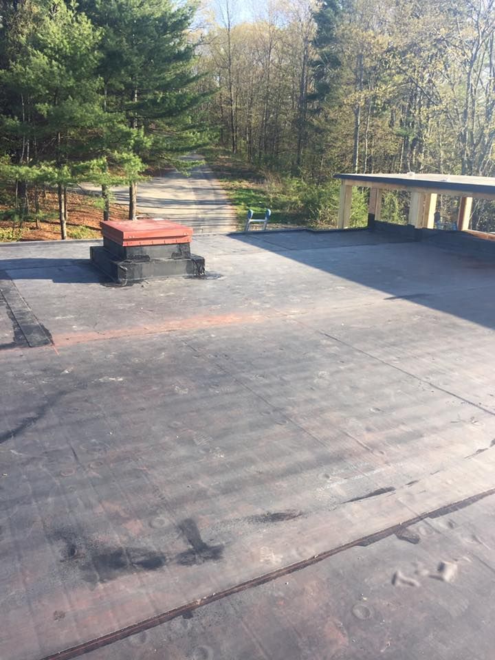 A black roof with a red chimney on top of it.