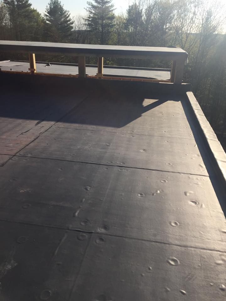 A black roof with trees in the background