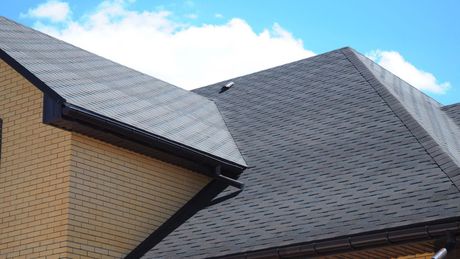 A close up of a roof of a house with a blue sky in the background.