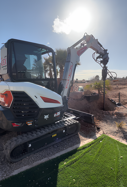 A small excavator is sitting on top of a lush green field.