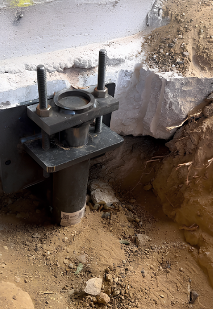A piece of metal is sitting in the dirt next to a rock.