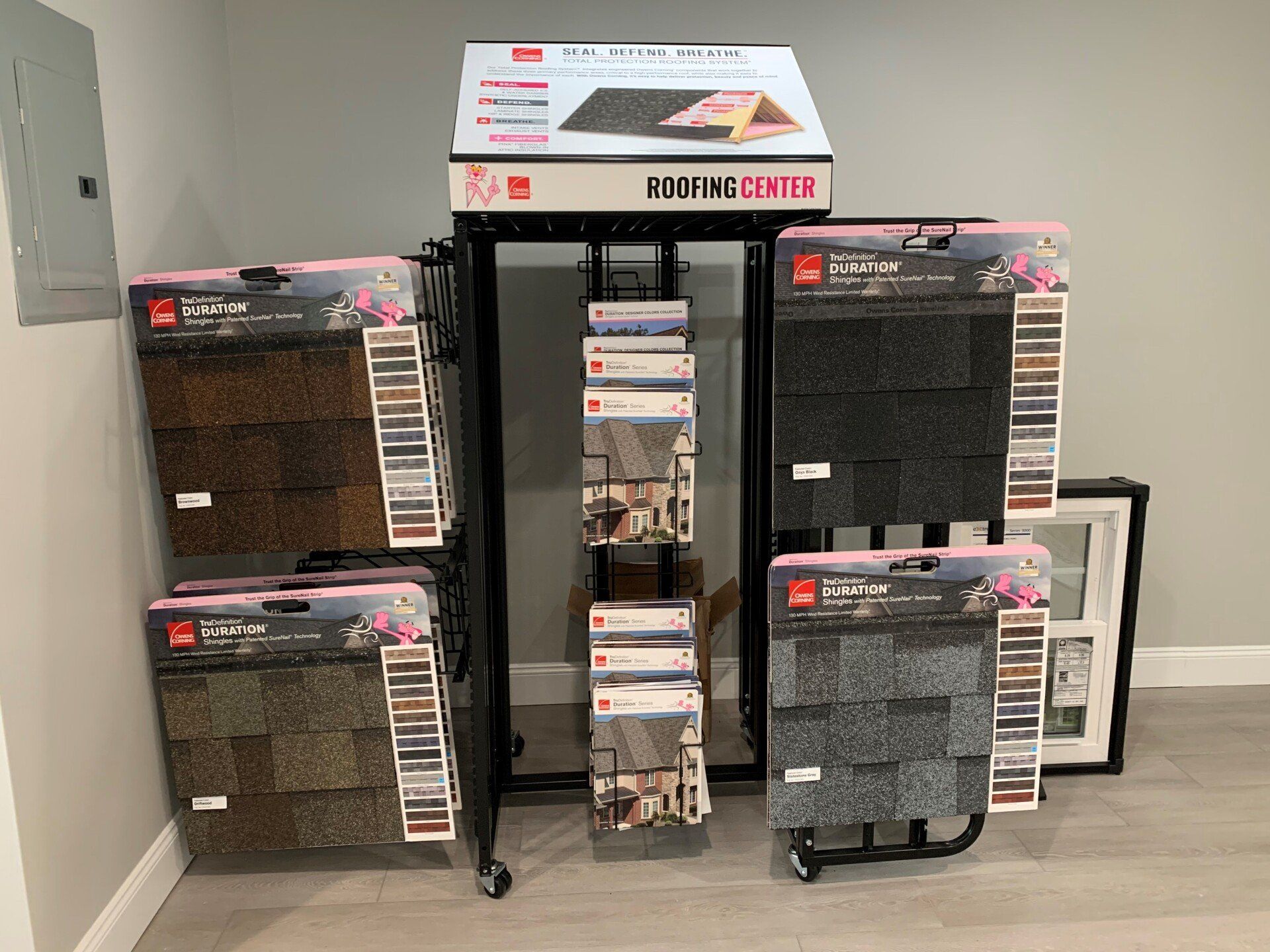 Display stand featuring various roof shingle samples in different colors, with a black frame and product information.