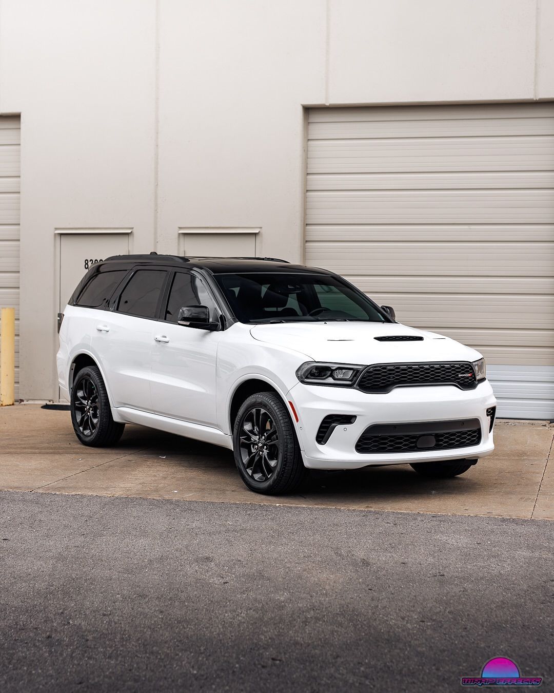 White Dodge Durango SUV with black accents parked outside a light-colored building.