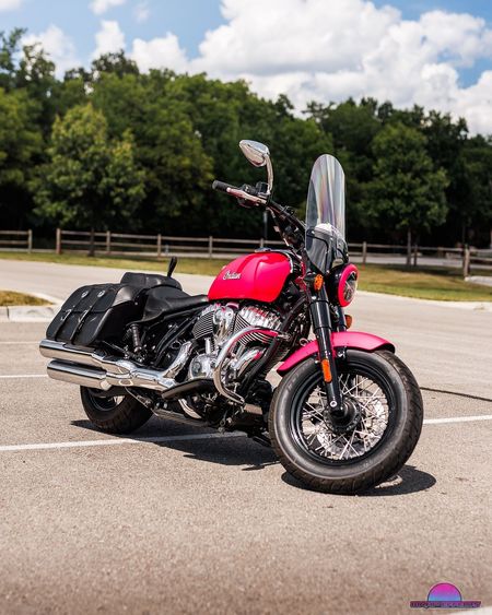 Pink Indian motorcycle parked on pavement.