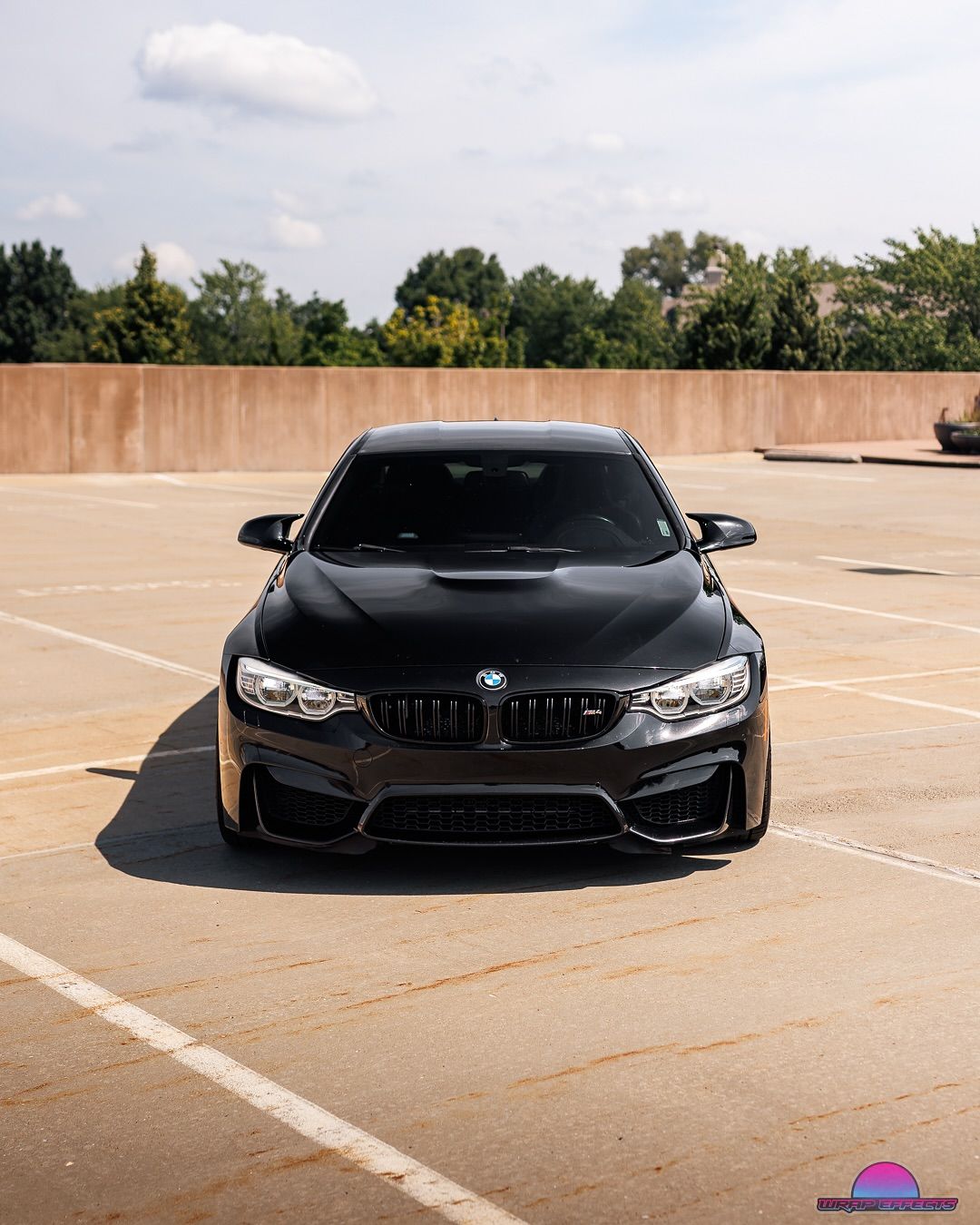 Black BMW M3 sports car parked on a parking lot. Sunny day, medium shot.