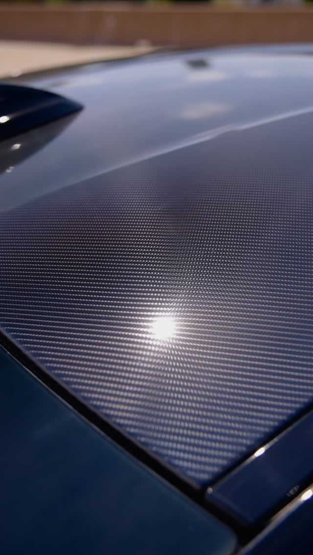 Carbon fiber car roof reflecting sunlight.