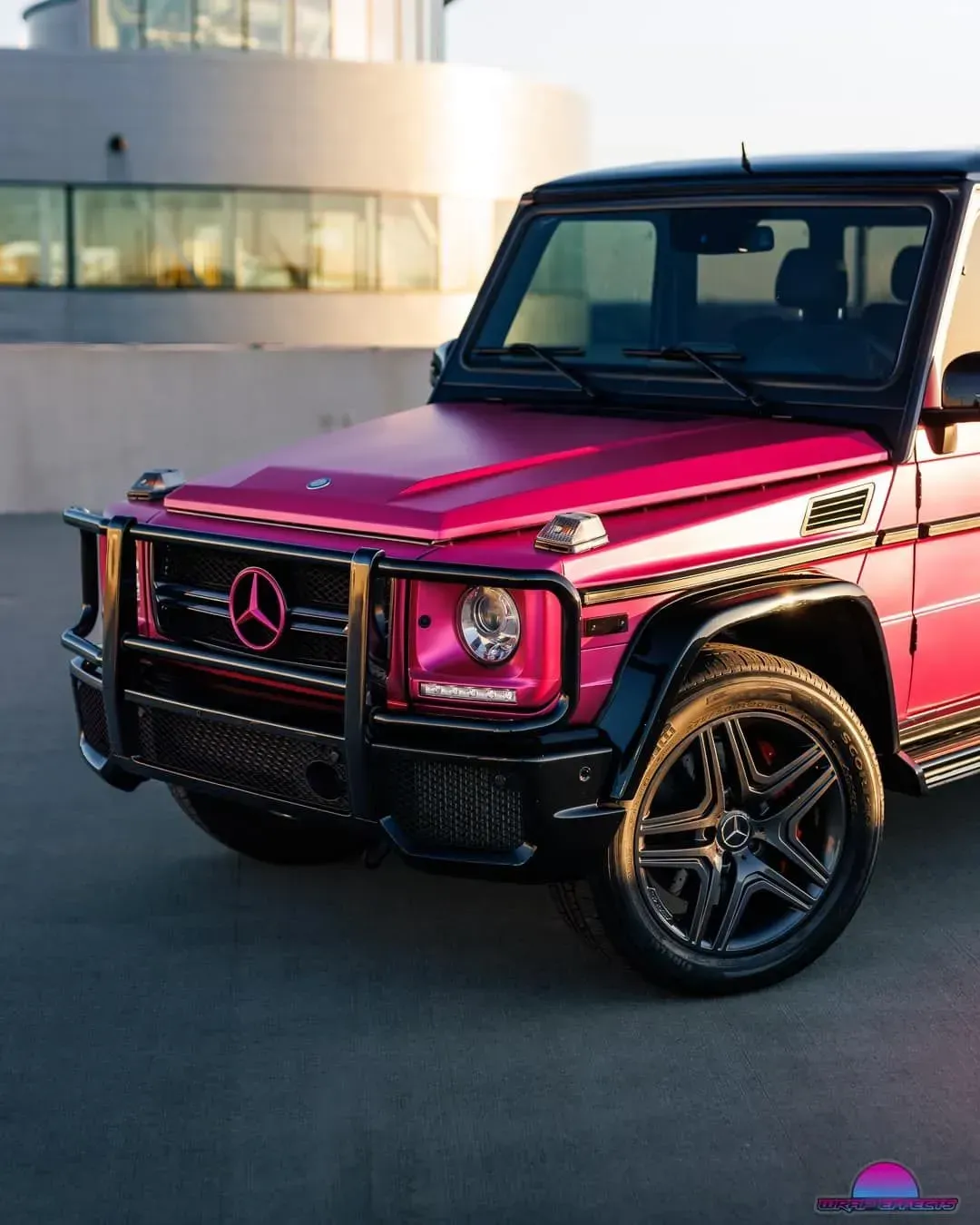 Pink Mercedes-Benz G-Class SUV with black accents parked in a modern setting.