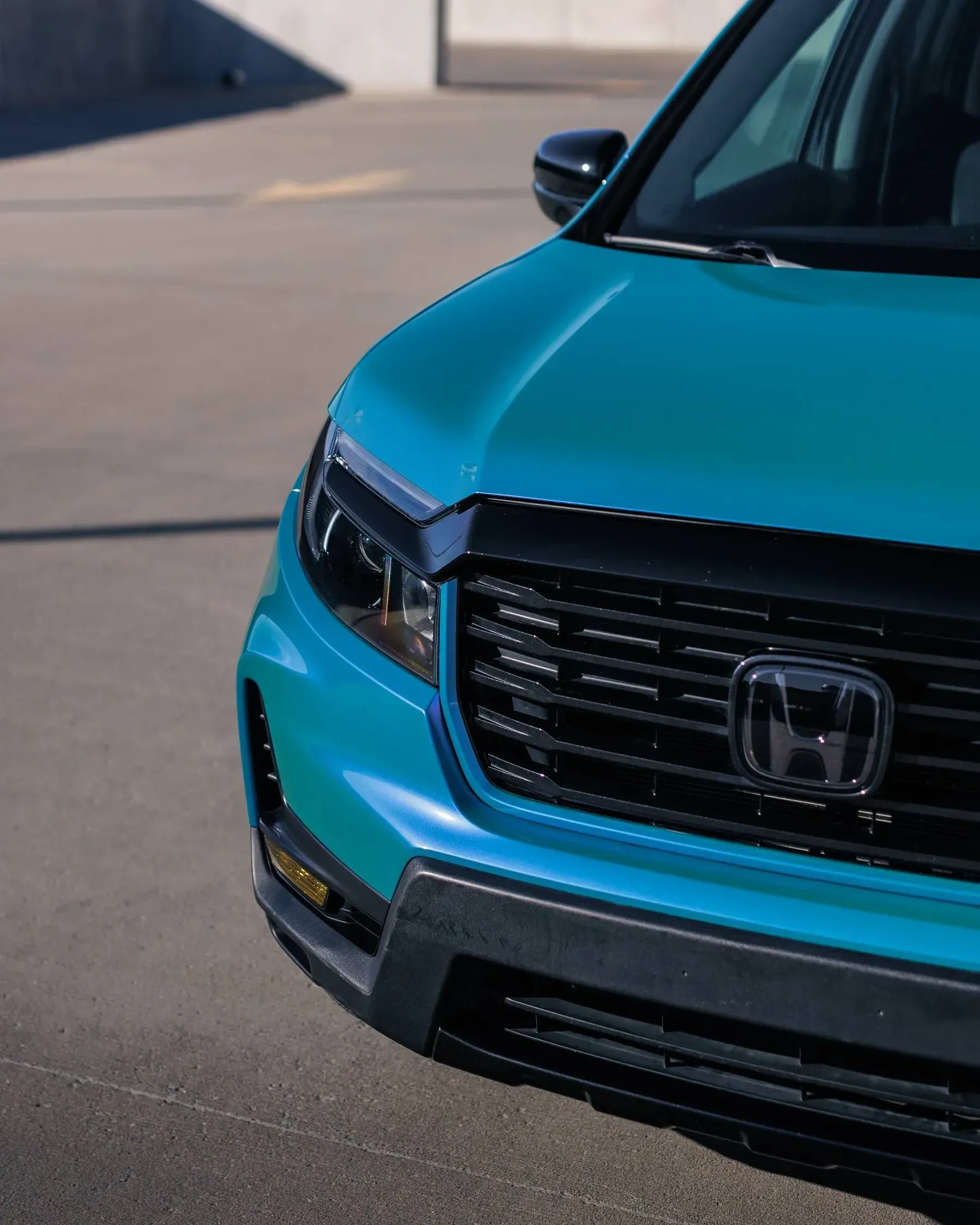 Blue Honda truck front corner. Black grille, bumper, and trim. Daytime, outdoor.