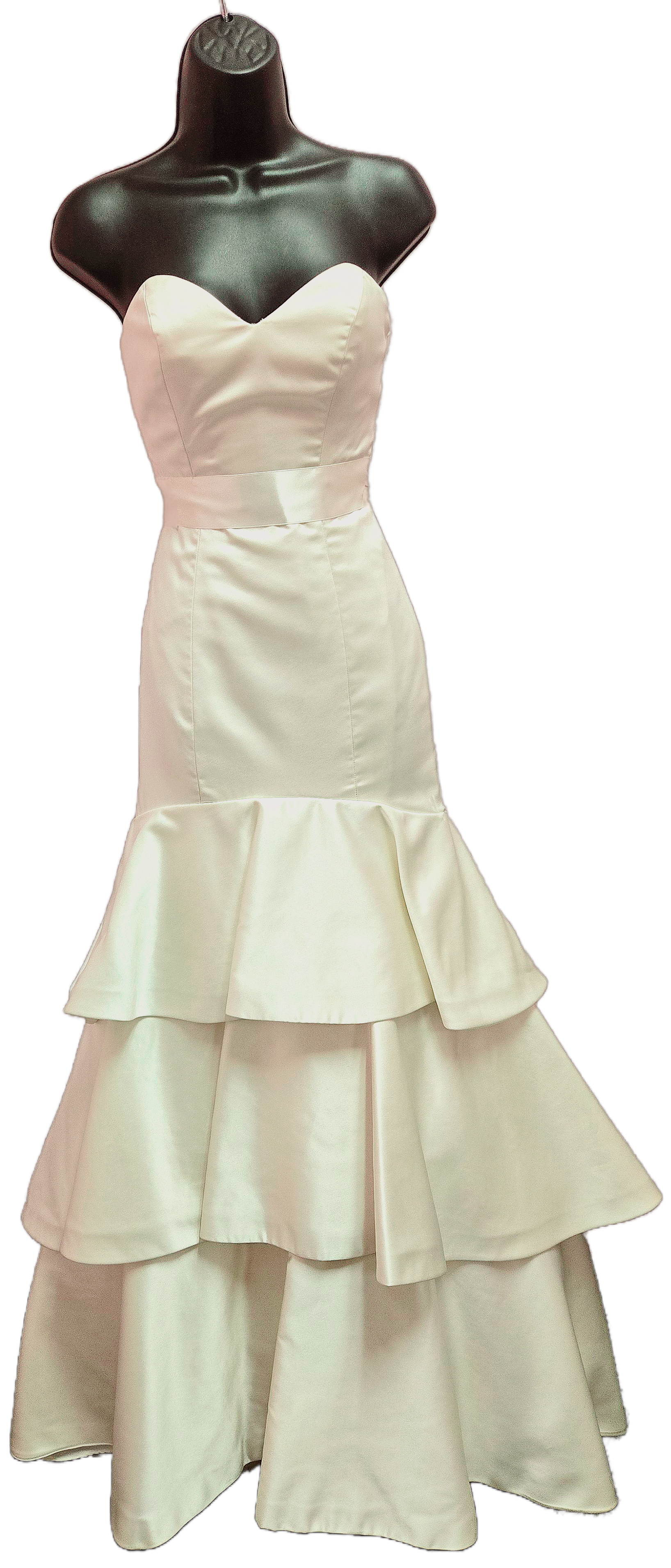 Cream-colored strapless wedding dress on a black mannequin; fitted bodice, belted waist, and tiered, flounced skirt.