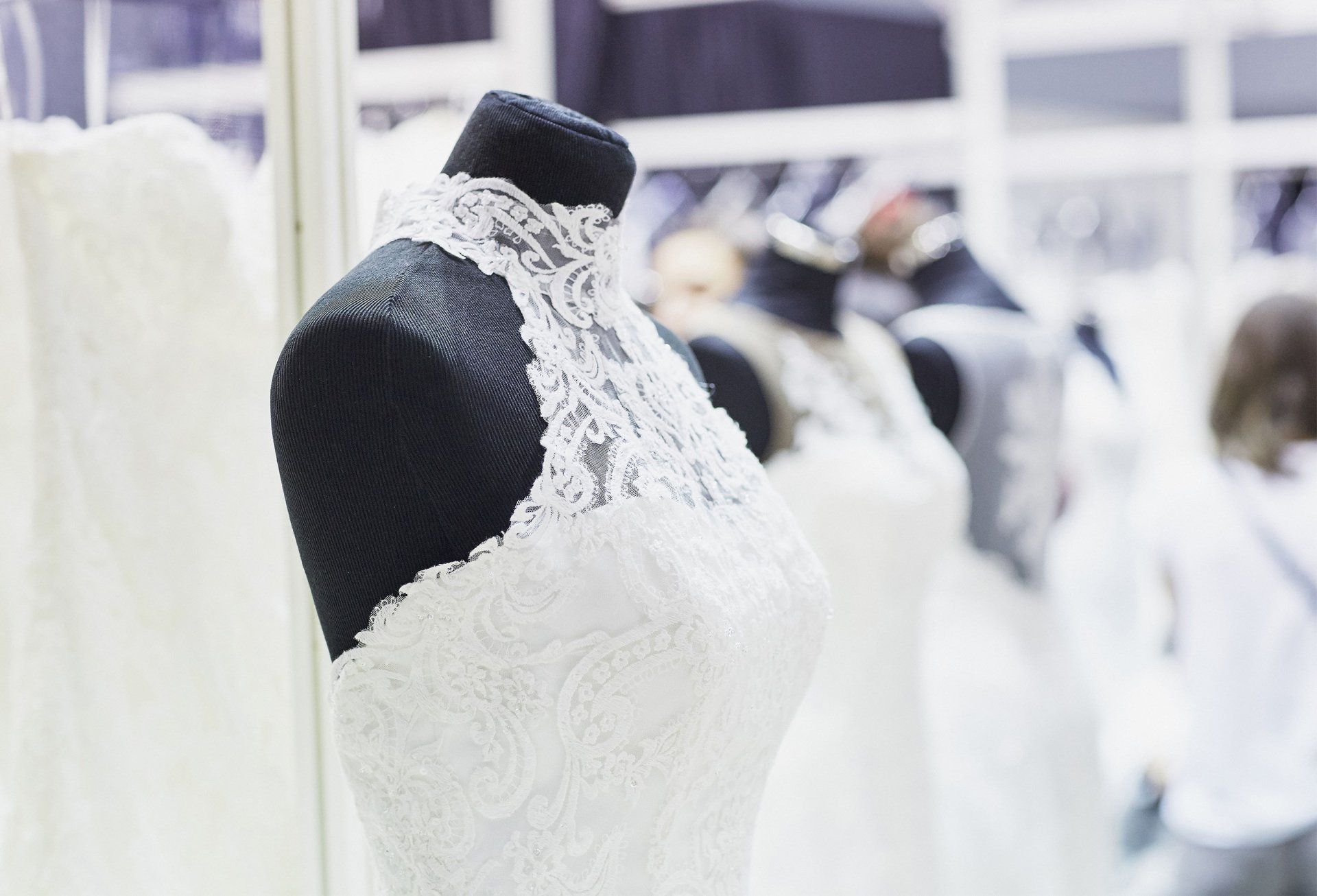 White lace wedding dress on a black mannequin, in a bridal shop.