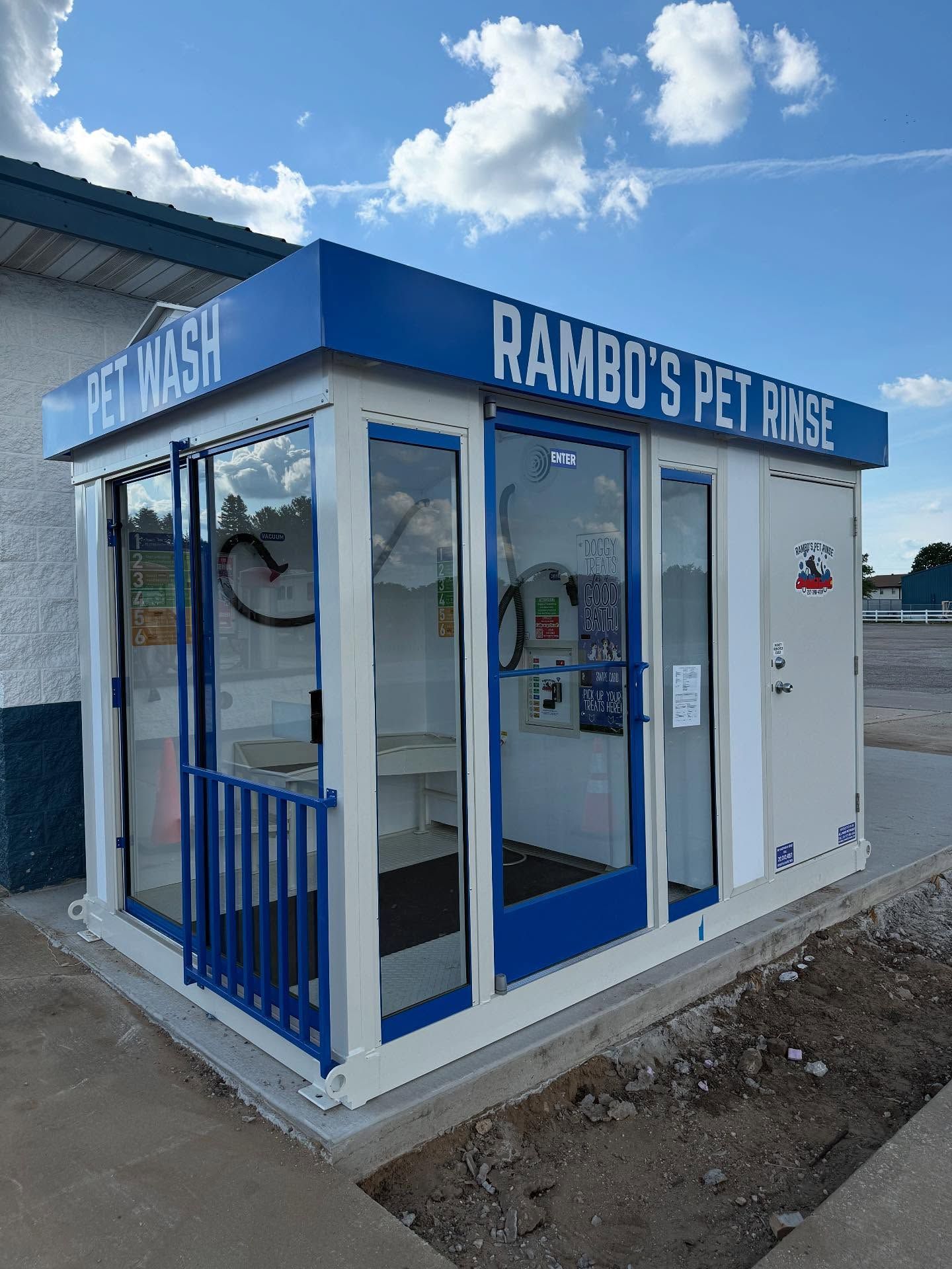 Rambo's Pet Rinse: Outdoor self-service dog wash station, blue and white with glass doors.
