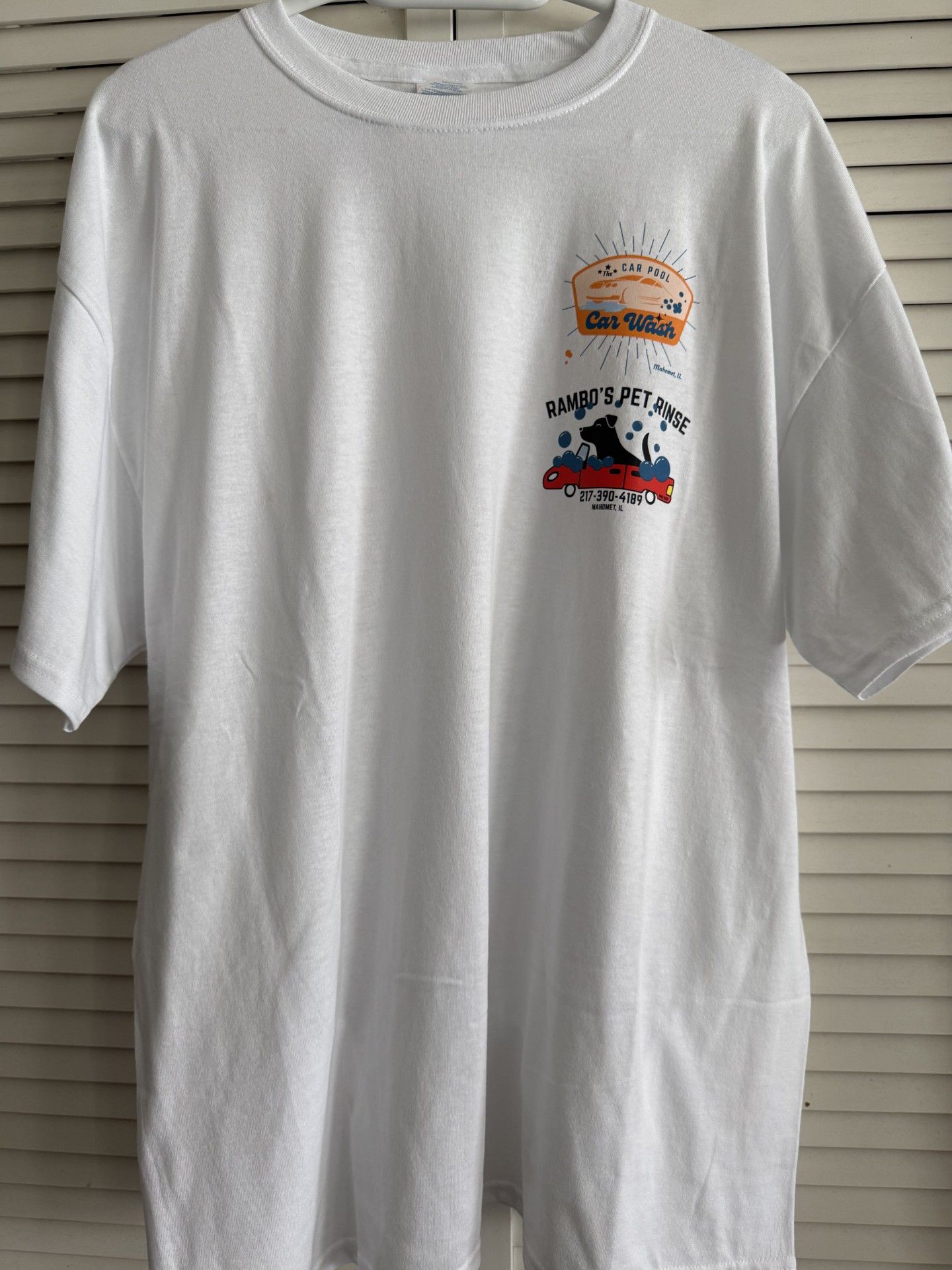 White t-shirt with a small graphic of a sunset and text, and a graphic of a truck with a silhouette.