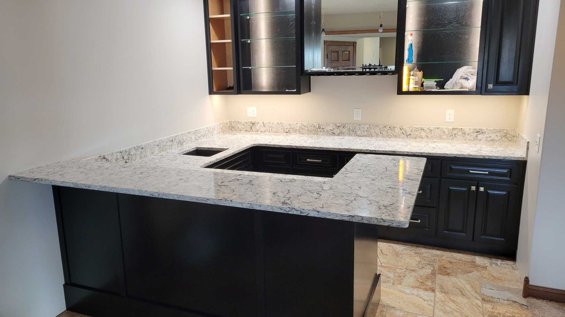 Kitchen with black cabinets and white granite countertops, stove inset.