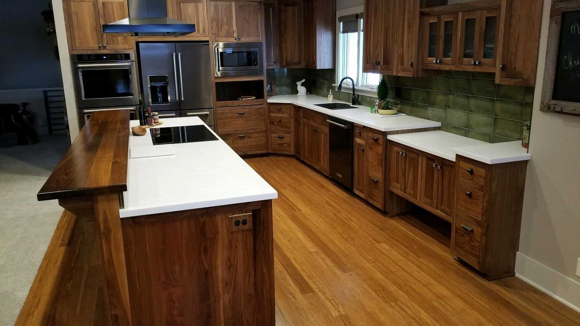 Modern kitchen with wood cabinets, white countertops, and stainless steel appliances.