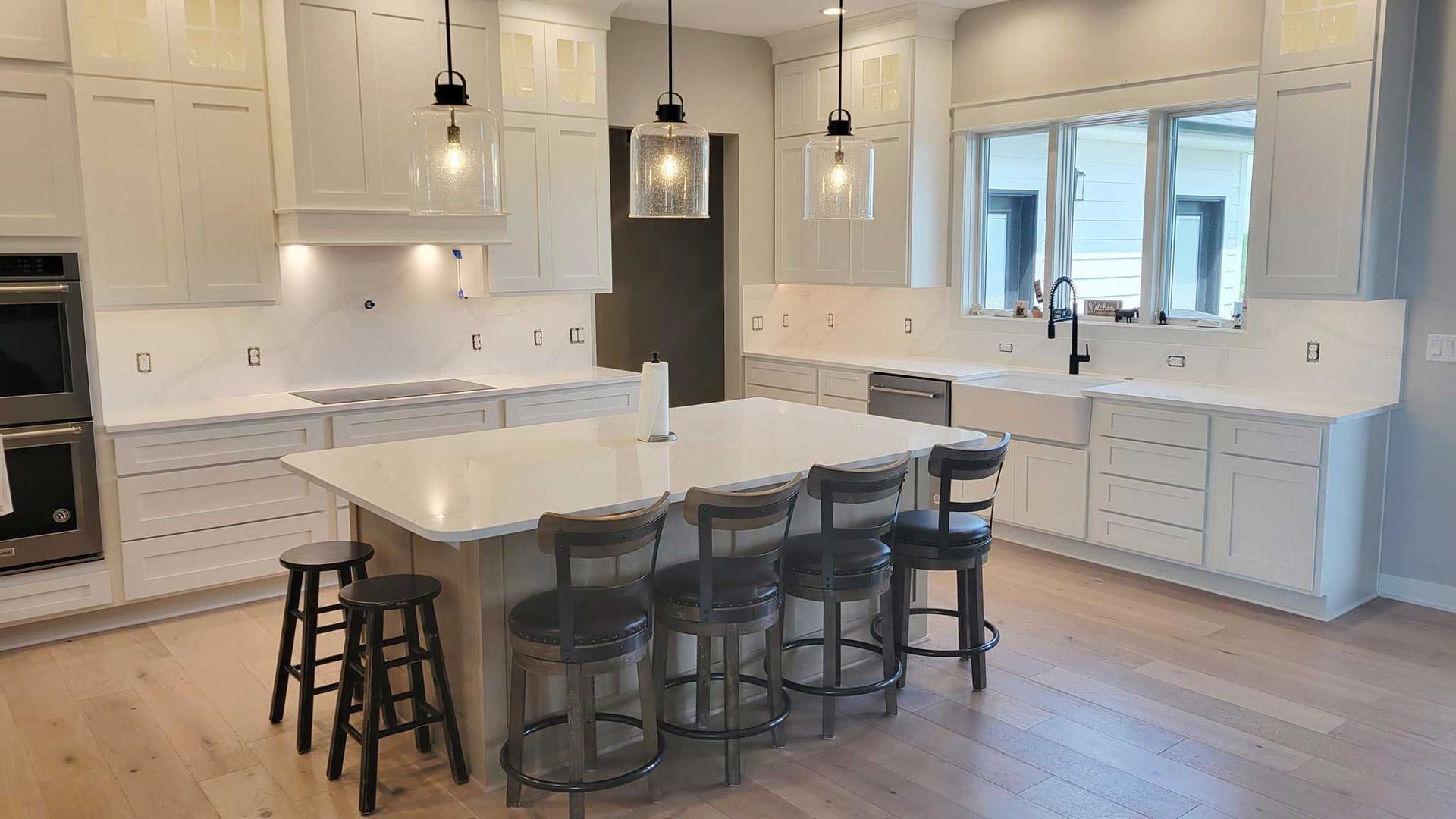 Modern kitchen with white cabinets, island with stools, and pendant lights.
