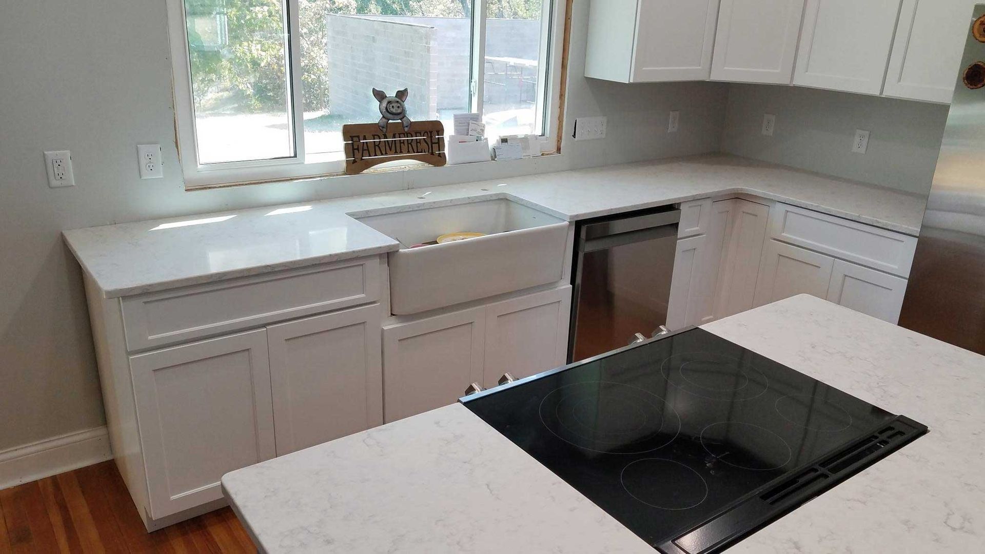 White kitchen with quartz countertops, cabinets, stainless steel appliances, and island.