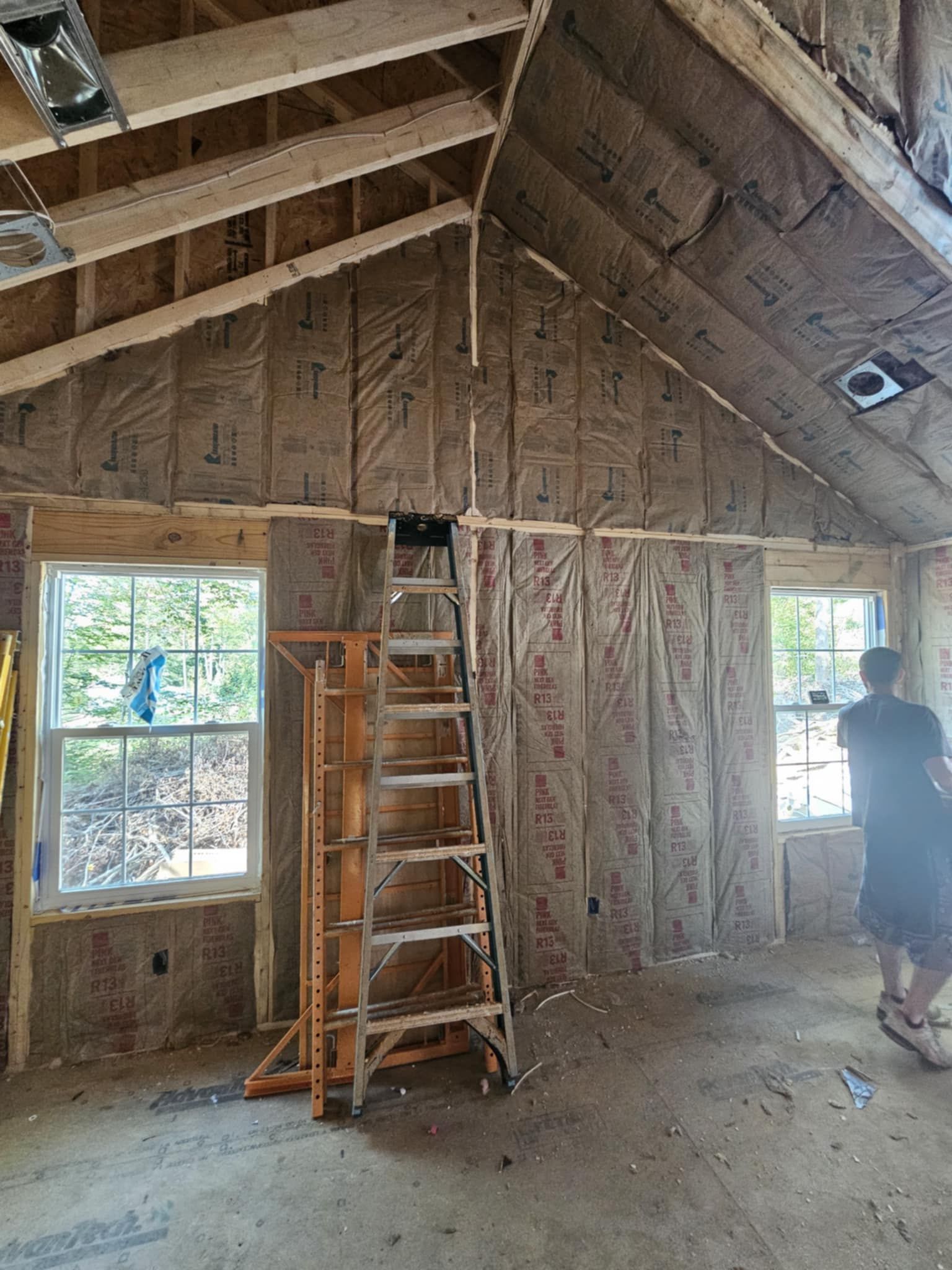 A man is standing in a room with a ladder in it.