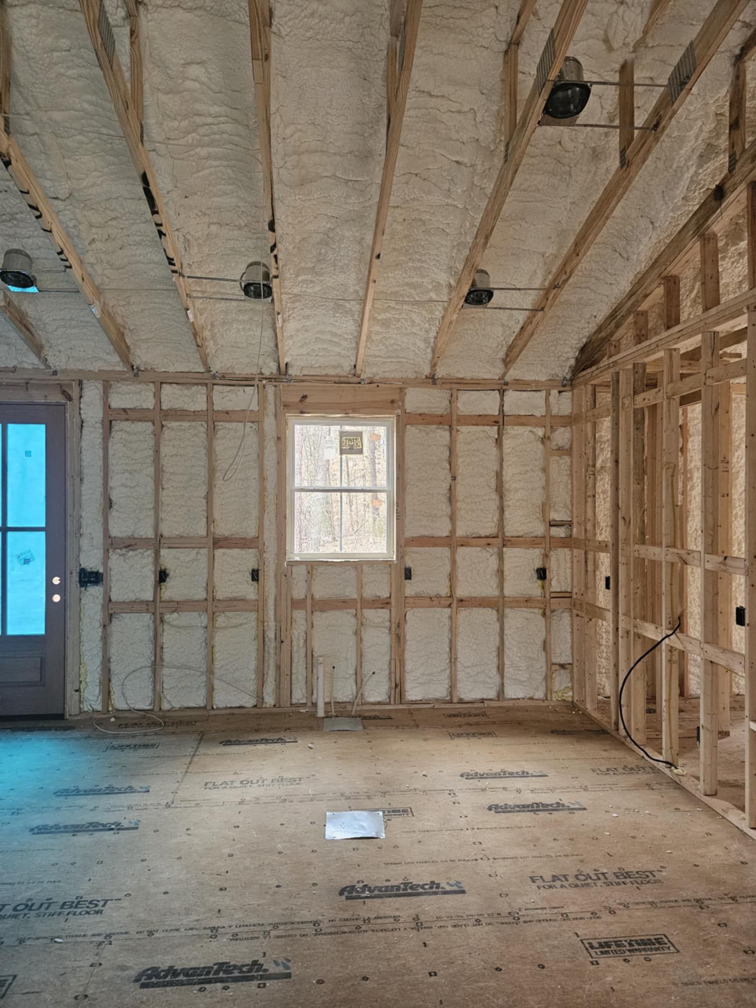 A room in a house under construction with insulation on the walls and ceiling.