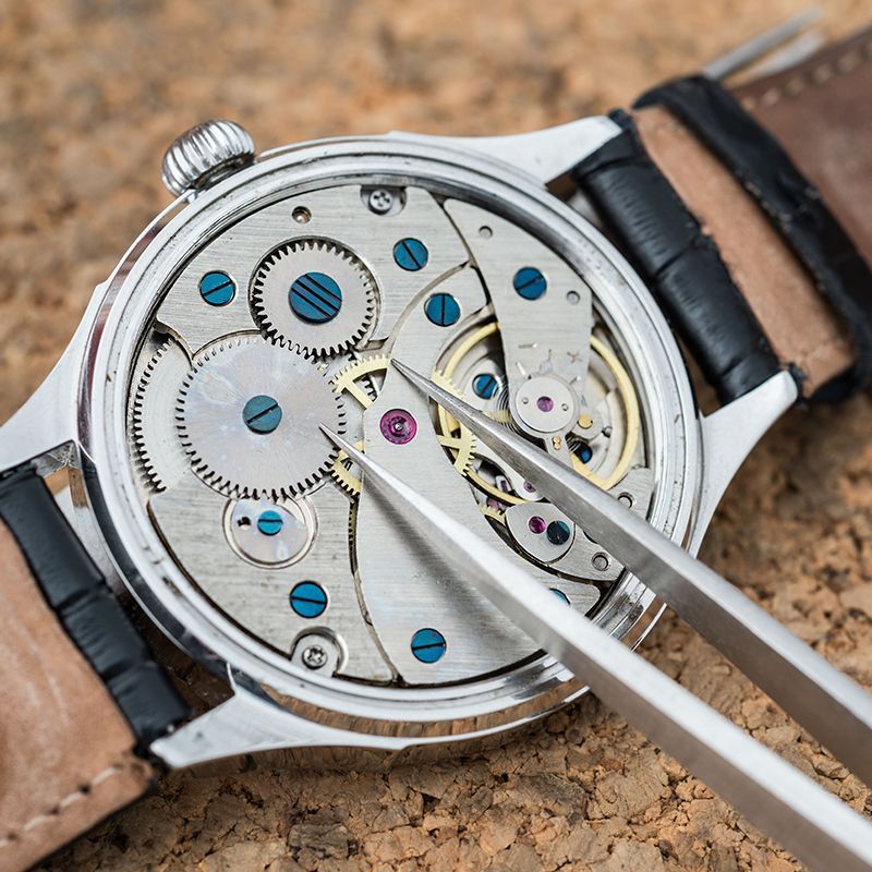 A close up of a watch being repaired with tweezers.