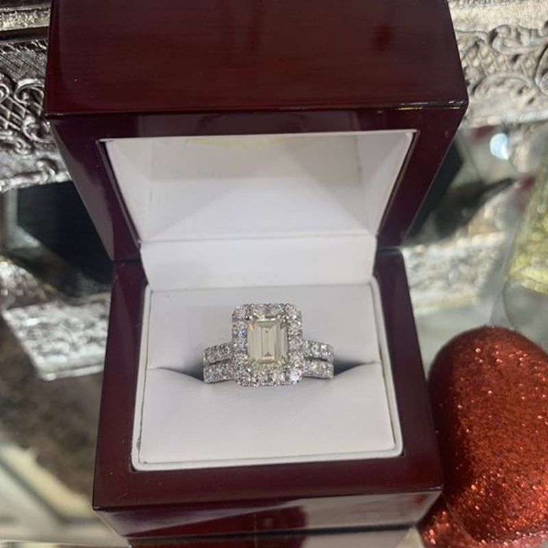 An emerald cut diamond ring is in a wooden box