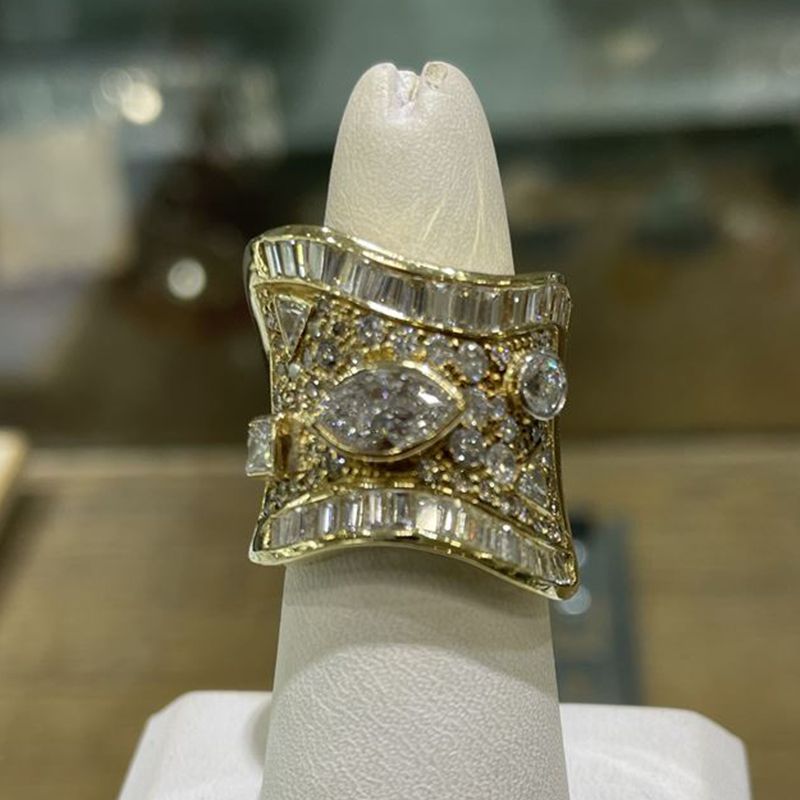 A gold ring with diamonds on a white ring holder