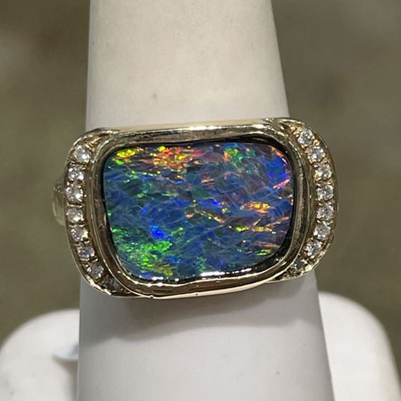 A ring with an opal and diamonds on a finger