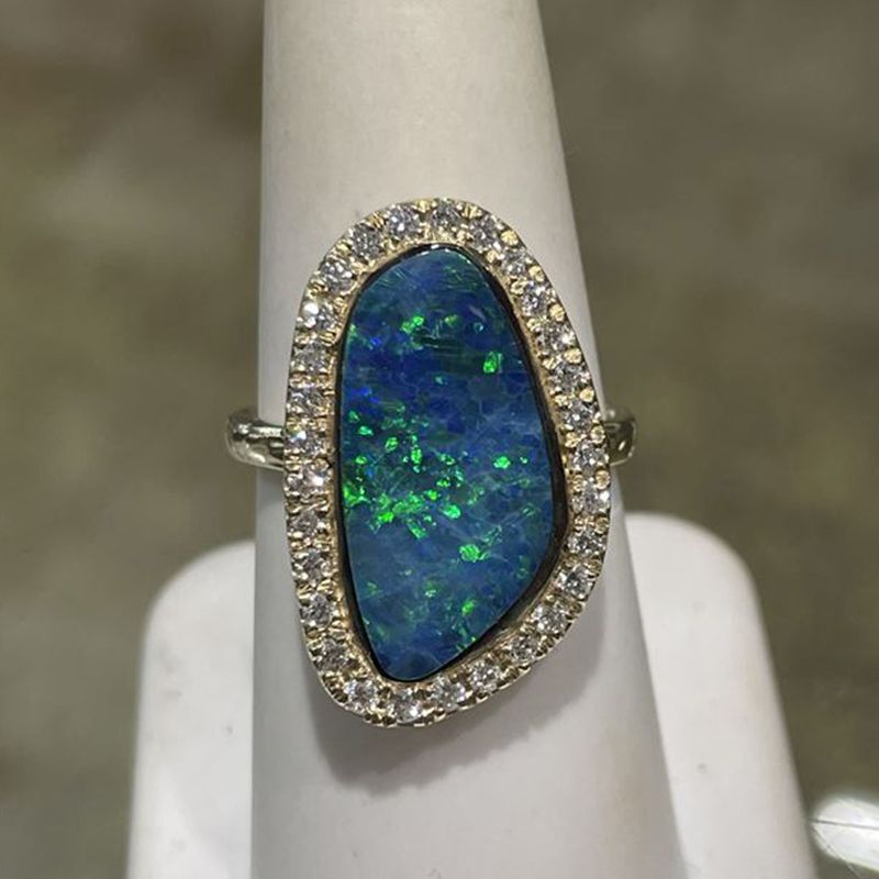 A ring with an opal and diamonds on a finger