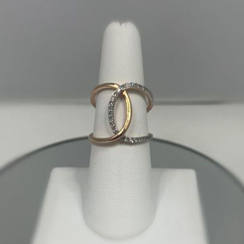 A gold and silver ring is sitting on a white ring holder.