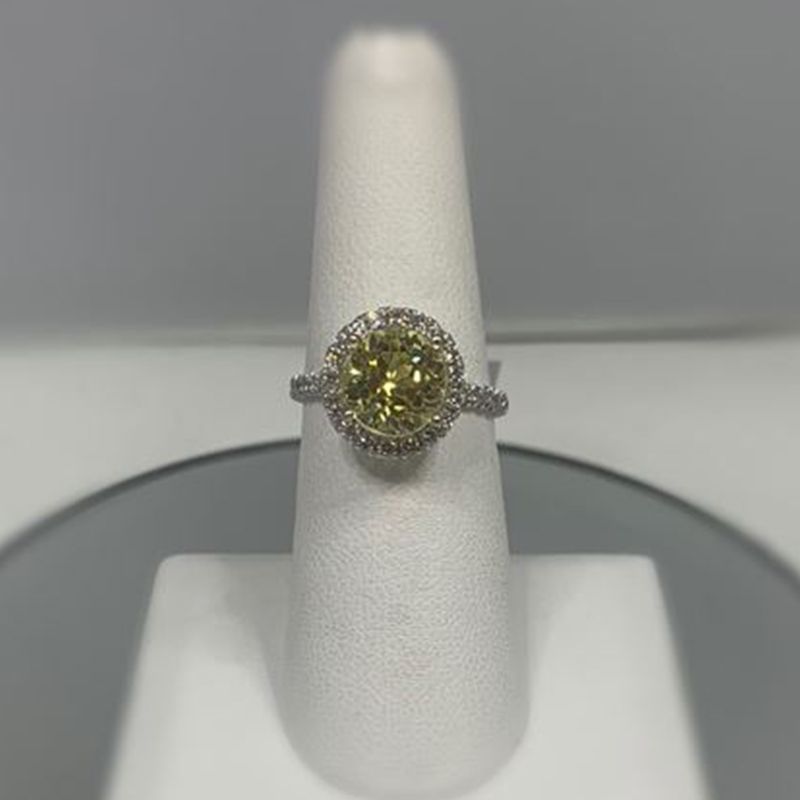 A yellow diamond ring is sitting on a white ring holder.