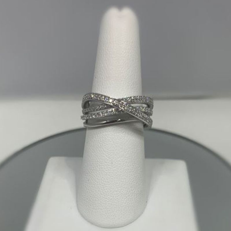 A silver ring with diamonds is sitting on a white ring holder.