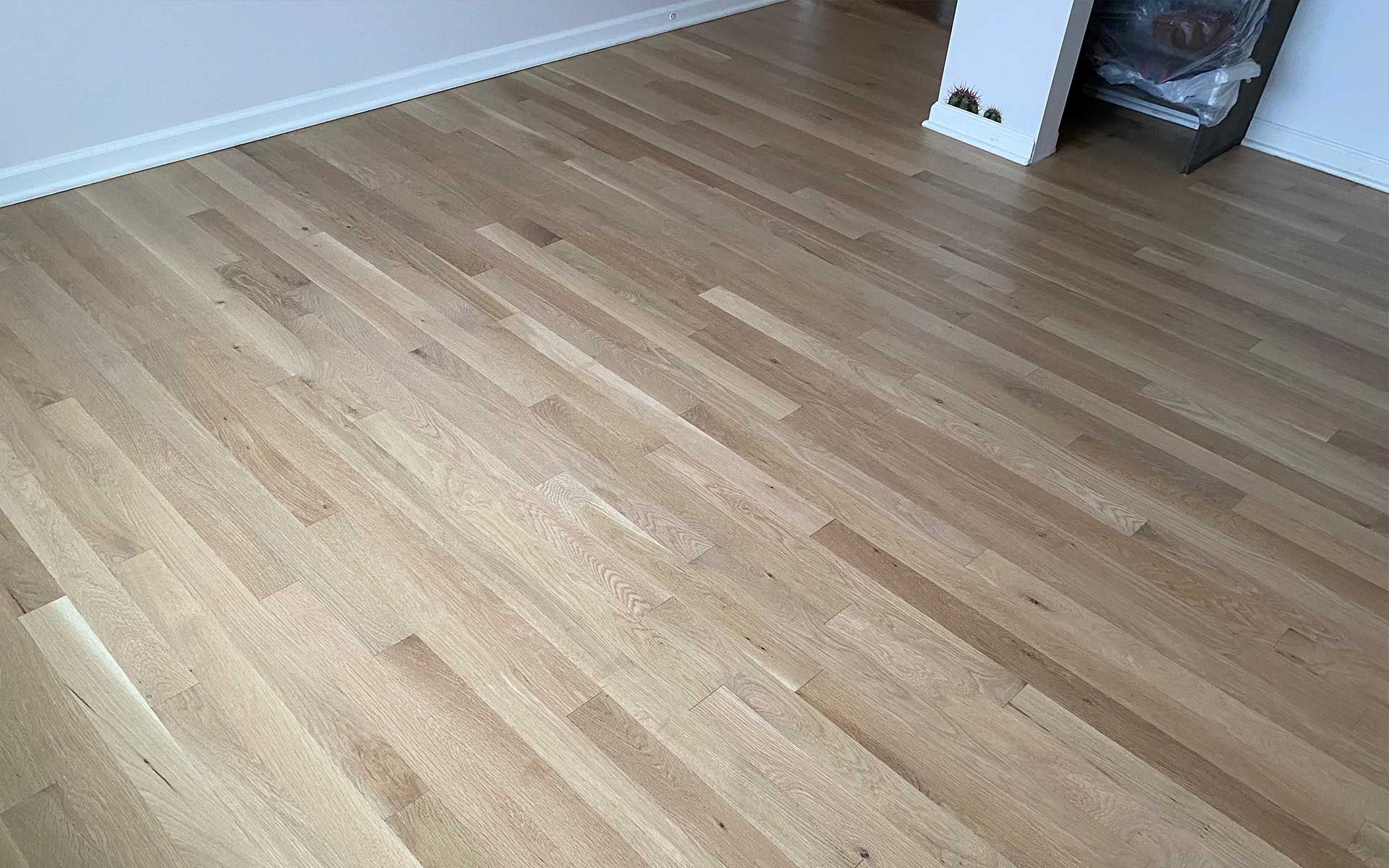 A wooden floor in a living room with a fireplace in the background.