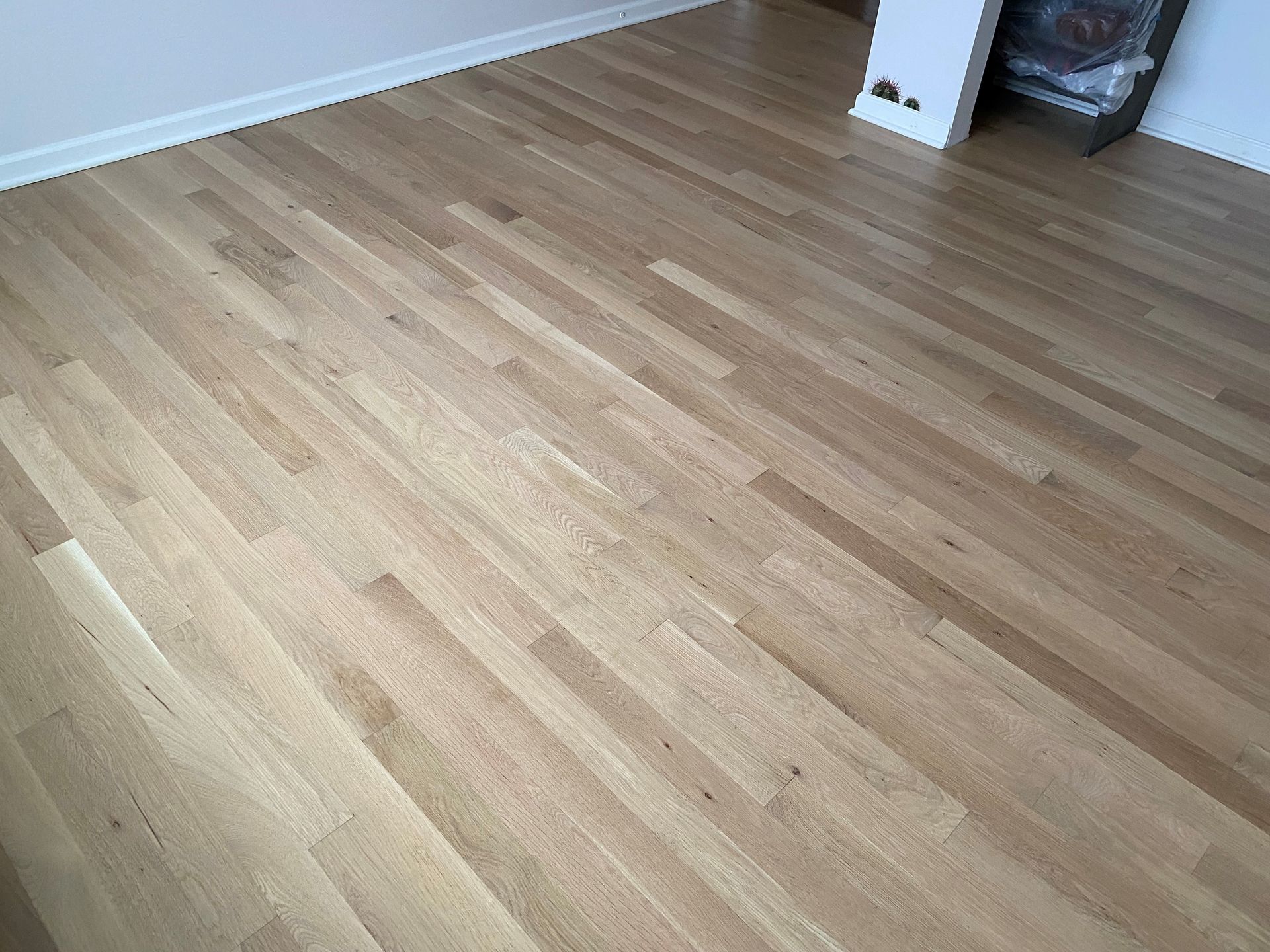 A wooden floor in a living room with a fireplace in the background.
