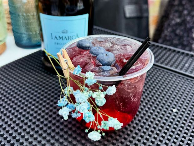 Blueberry drink on a bar mat, with a bottle in the background.