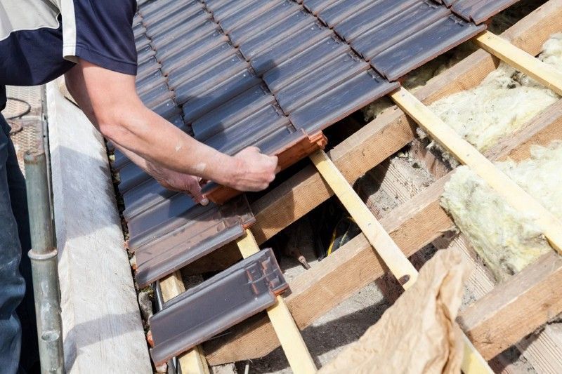 A man is installing tiles on a roof.