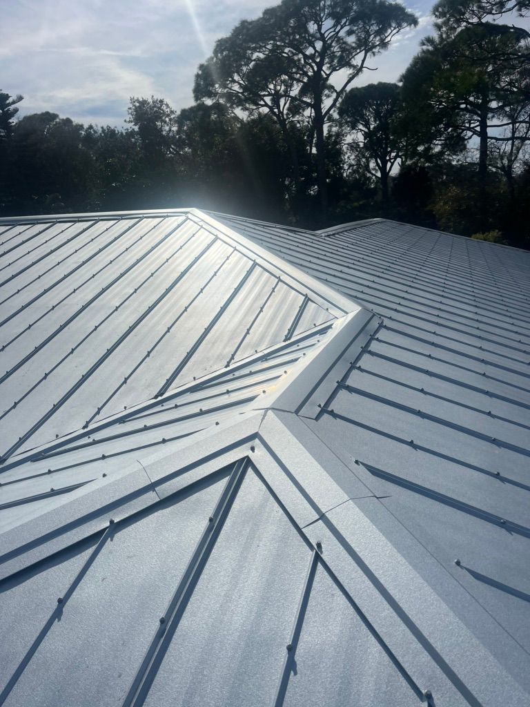 A close up of a metal roof with trees in the background.