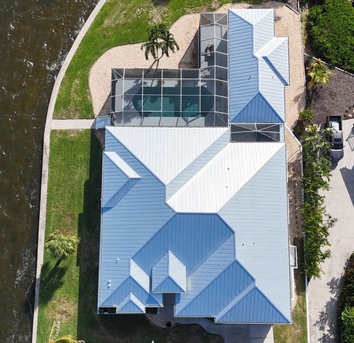 Aerial view of a house with a pool, angled roof, and canal access.