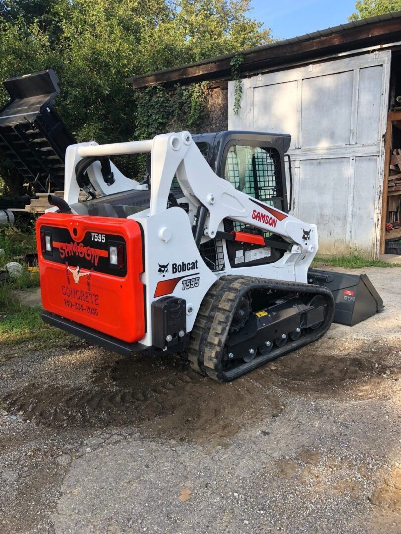A bobcat track loader is parked in front of a building.