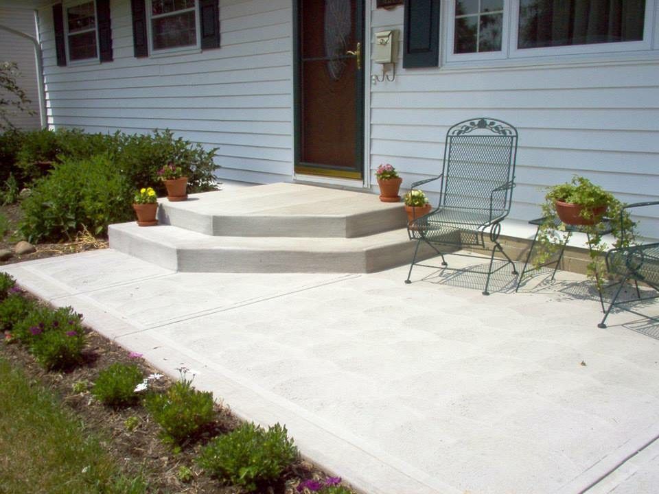 A patio with steps and chairs in front of a house.