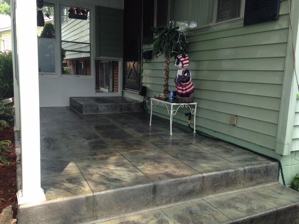 A concrete porch with steps and a table in front of a house.